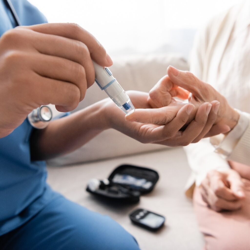 Ausschnitt einer multiethnischen Krankenschwester, die einer älteren Frau mit einer Lanzette Blut abnimmt.