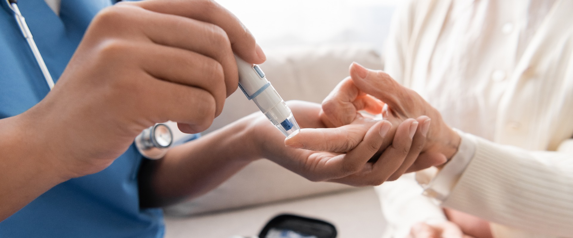 Ausschnitt einer multiethnischen Krankenschwester, die einer älteren Frau mit einer Lanzette Blut abnimmt.