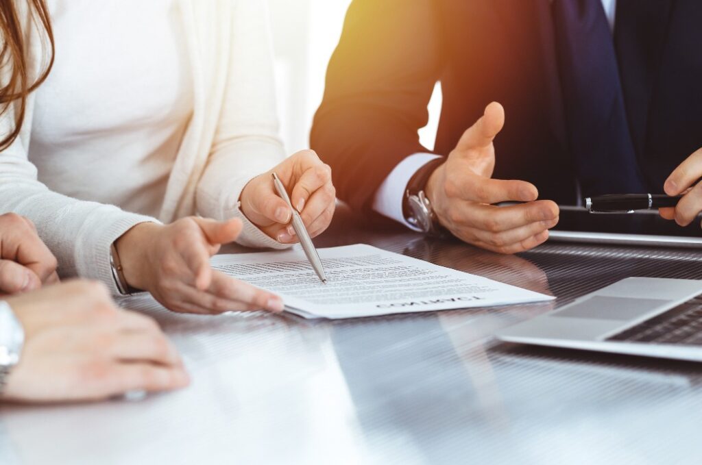 Geschäftsleute besprechen einen Vertrag, während sie in einem hellen, modernen Büro zusammenarbeiten. Unbekannter Geschäftsmann und Frau mit Kollegen oder Anwälten bei einem Meeting.